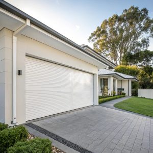 White roller garage door installed on modern Sutherland Shire home with coastal landscaping